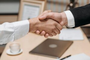 Close-up of two people shaking hands in an office, symbolizing agreement and partnership.